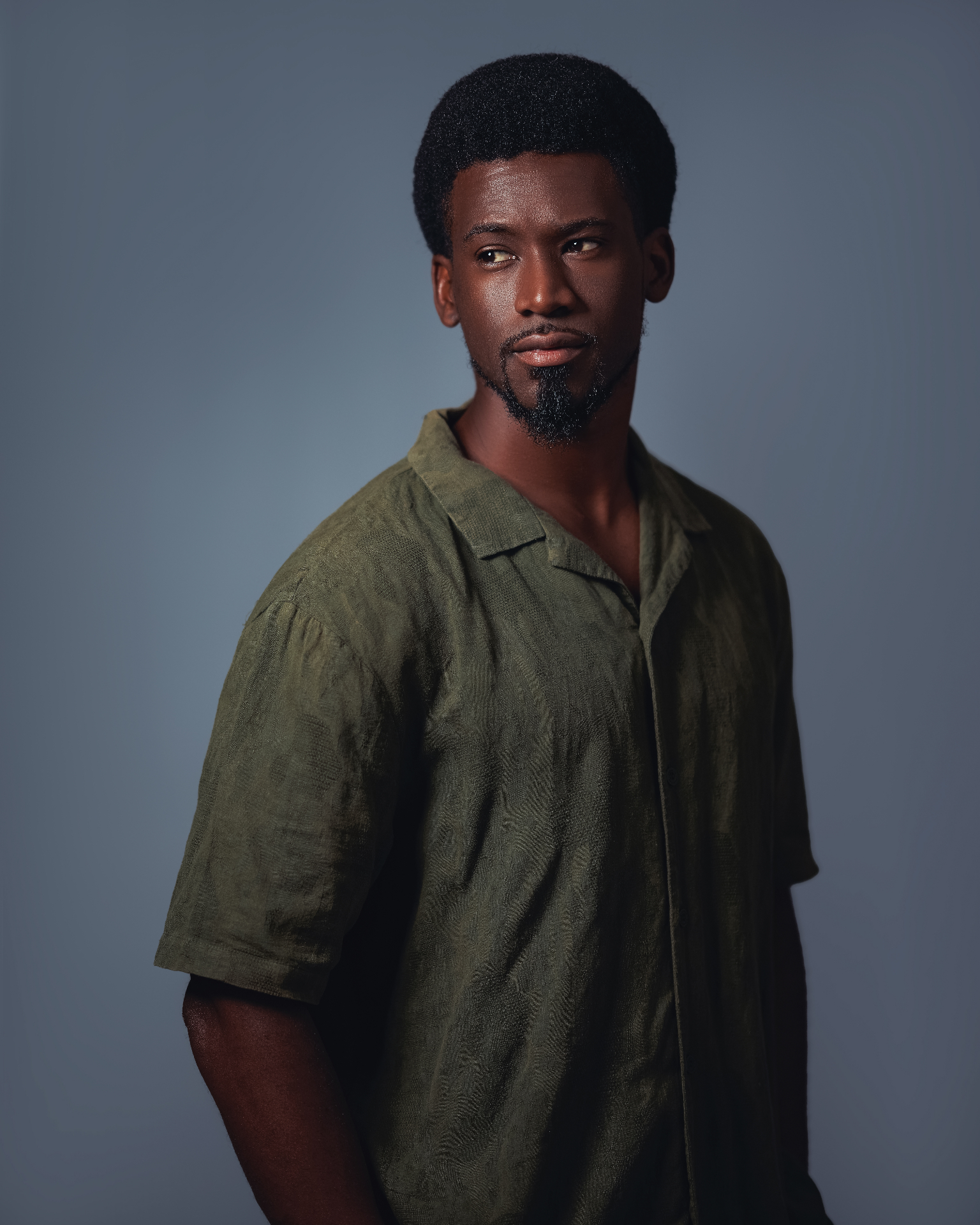 Kamanga wearing an olive shirt against a blue backdrop